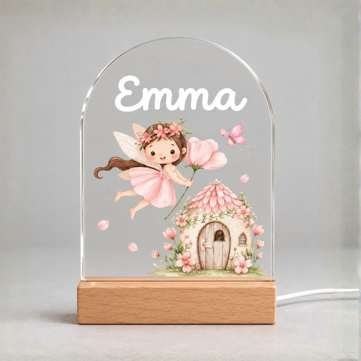 Front view of the clear arched panel with Emma, a pink fairy, a cottage, and a light wood-tone base.