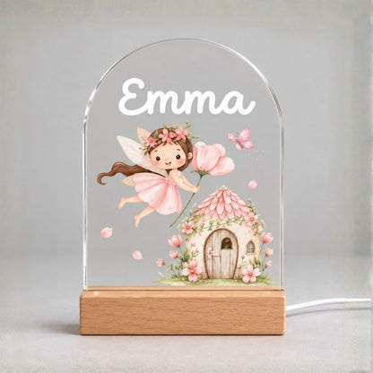 Front view of the clear arched panel with Emma, a pink fairy, a cottage, and a light wood-tone base.