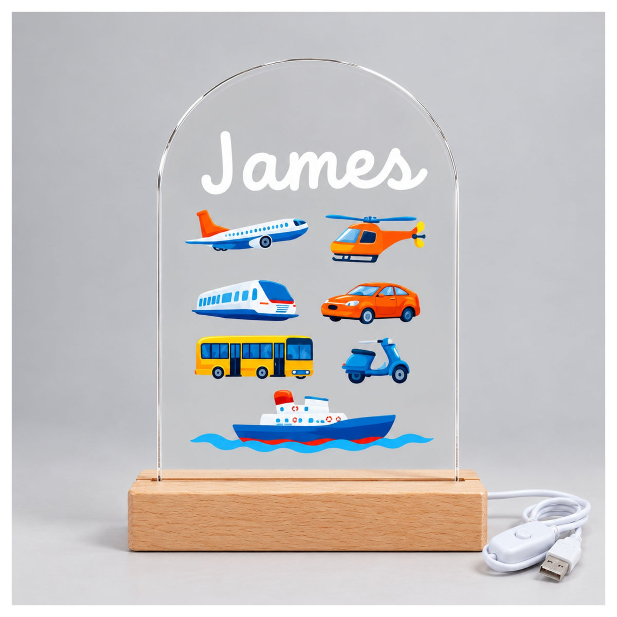 Front view of the unlit acrylic panel with the name James, colorful vehicles, and a white cable beside it.