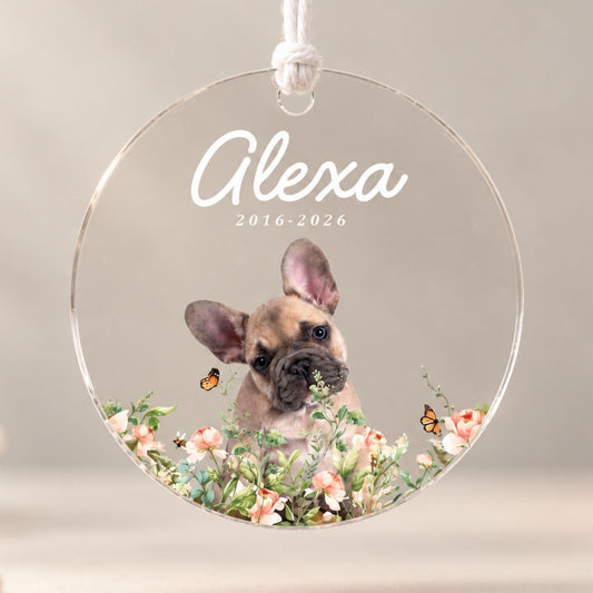 Studio front view of a round acrylic pet loss ornament printed with a French bulldog portrait, floral accents, and custom memorial dates on a neutral background.