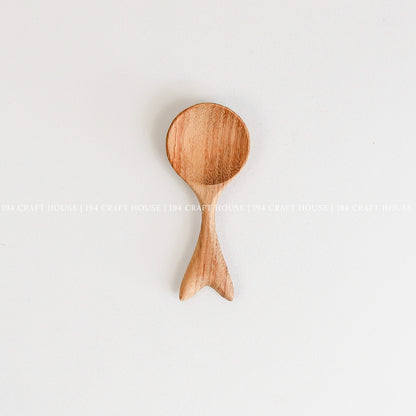 Handcrafted small wooden spoon with a decorative fishtail-shaped handle and smooth natural wood grain
