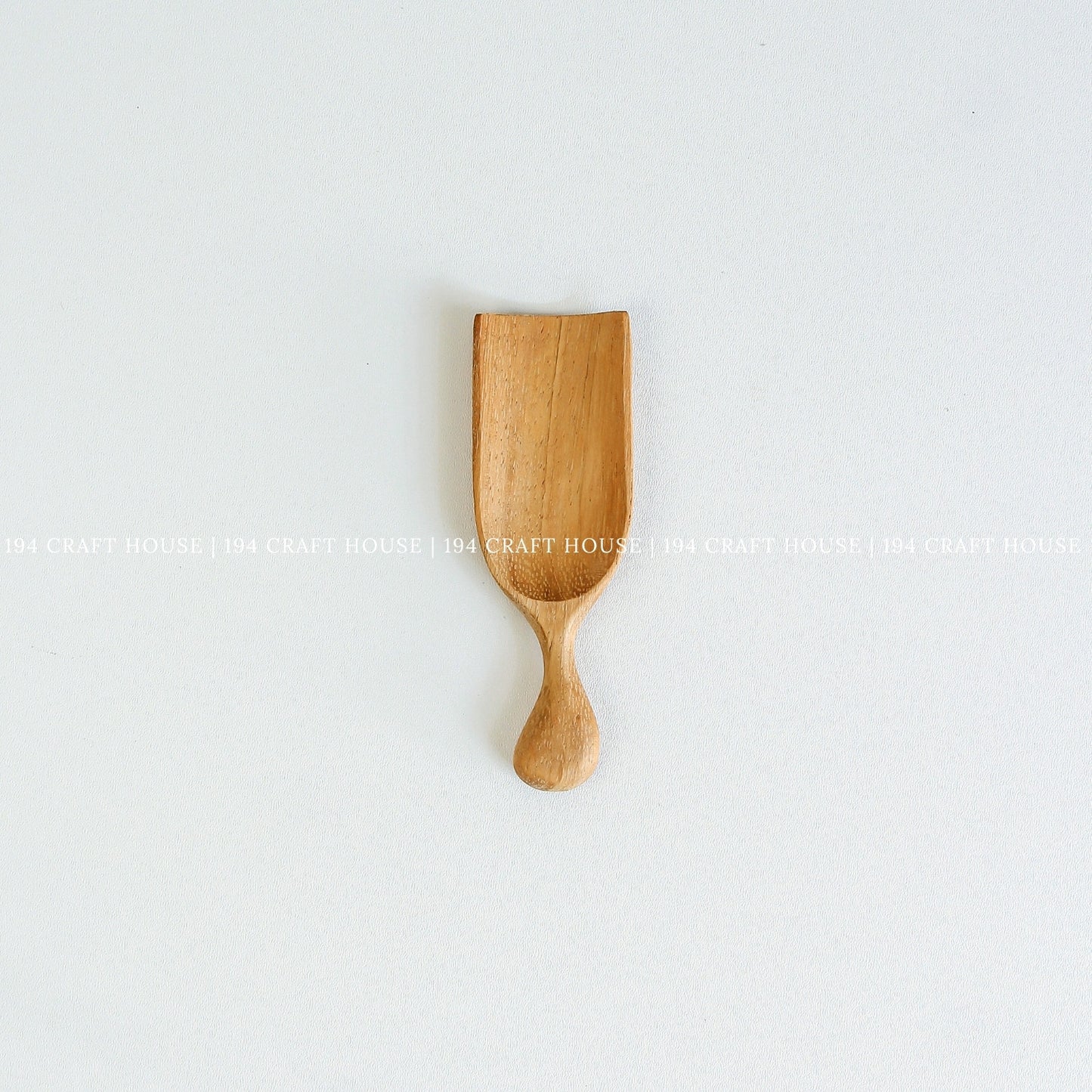Small handcrafted Doussie wood scoop with a smooth finish and natural wood grain