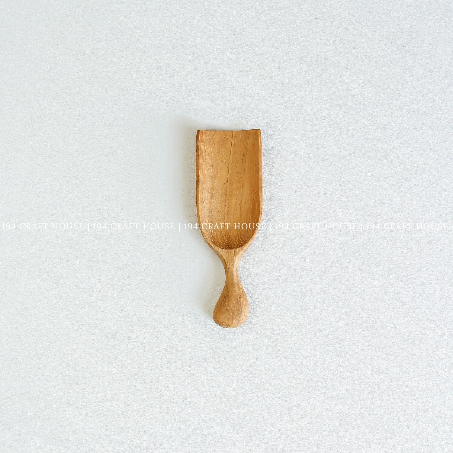 Small handcrafted Doussie wood scoop with a smooth finish and natural wood grain