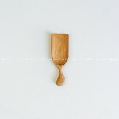 Small handcrafted Doussie wood scoop with a smooth finish and natural wood grain