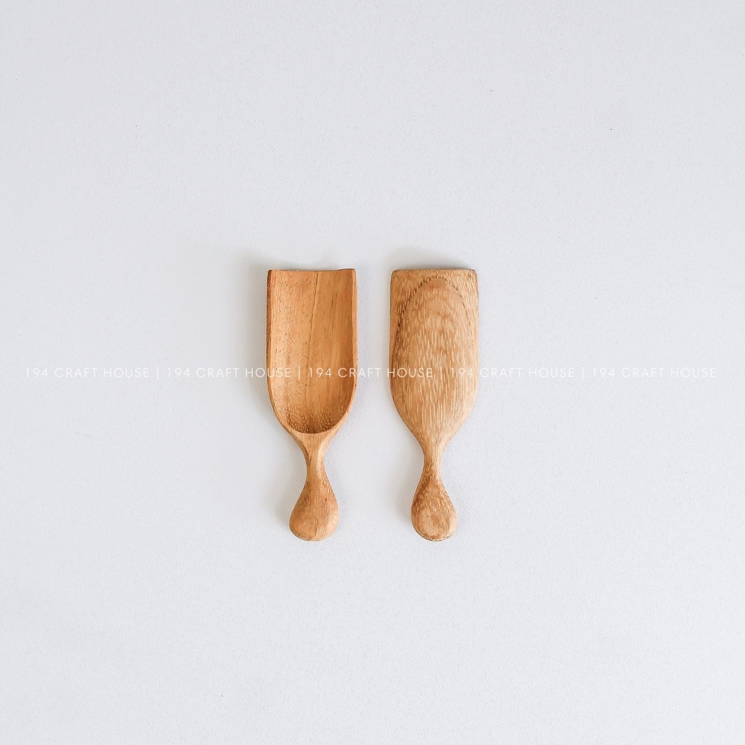 Two handcrafted small wooden bath scoops with natural wood grain and smooth artisan finishes