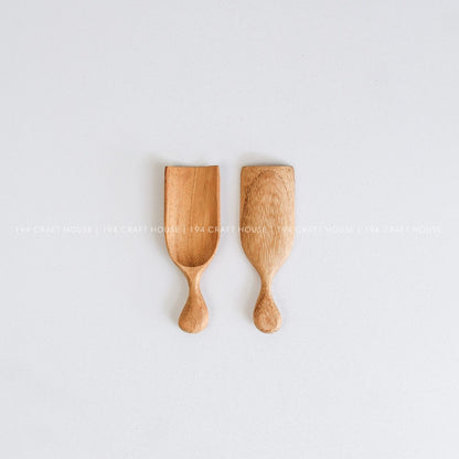 Two handcrafted small wooden bath scoops with natural wood grain and smooth artisan finishes