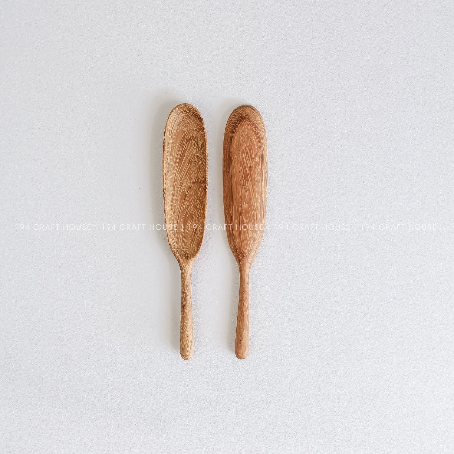 Two handcrafted long-handle wooden spice spoons with smooth artisan finish and natural wood grain