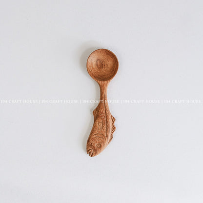 Hand-carved fish-shaped wooden measuring spoon with natural wood grain and artisan craftsmanship