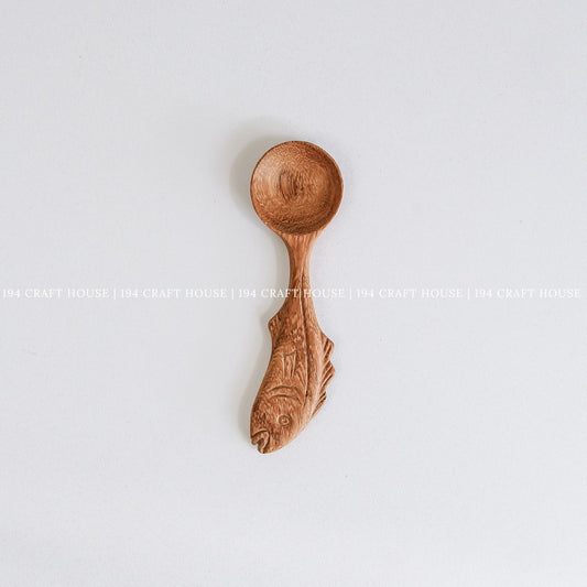 Hand-carved fish-shaped wooden measuring spoon with natural wood grain and artisan craftsmanship