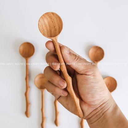 Handcrafted branch tree wooden spoon held in hand to show its size, shape, and natural wood grain