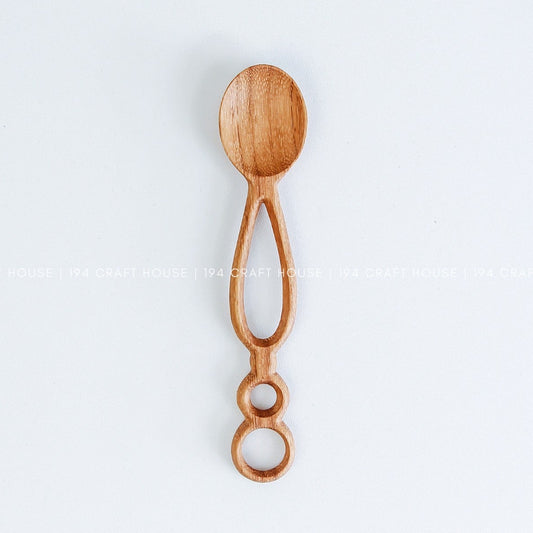 Handcarved Doussie wooden spoon with a round bowl and a unique handle featuring open geometric cutouts and holes, displayed against a white background.