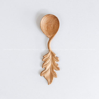 Handcrafted wooden spoon with a decorative leaf-shaped handle and natural wood grain