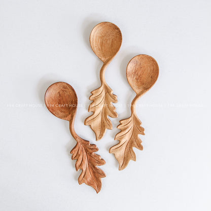 Close-up of handcrafted wooden spoons with decorative leaf-shaped handles and natural artisan details