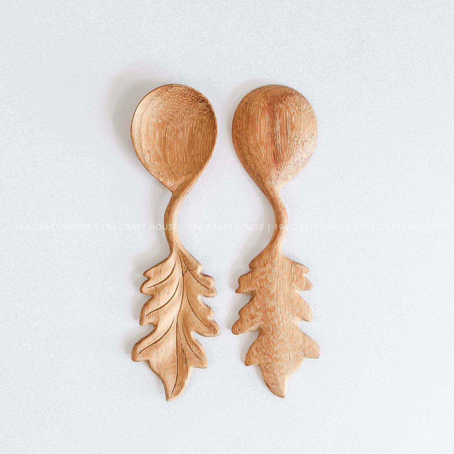 Two handcrafted wooden spoons with decorative leaf-shaped handles and smooth natural wood finish