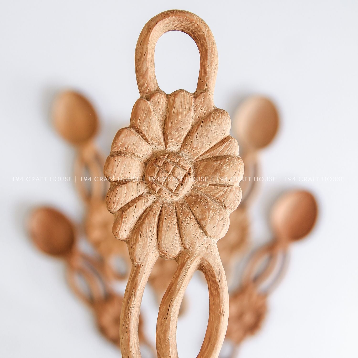 Handcrafted flower-shaped wooden spoons held in hand to show their size, shape, and natural wood grain