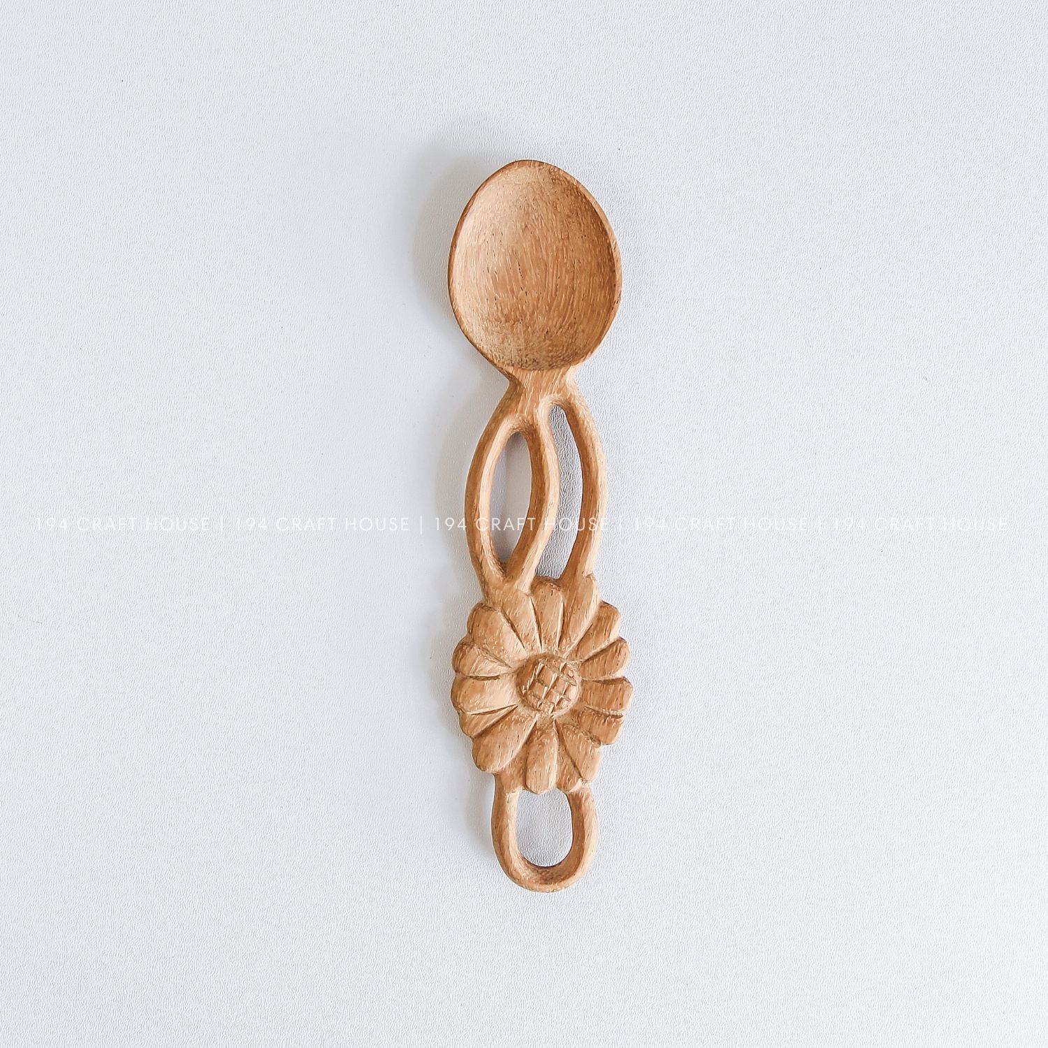 Handcarved wooden spoon with a decorative flower-shaped handle and natural wood grain