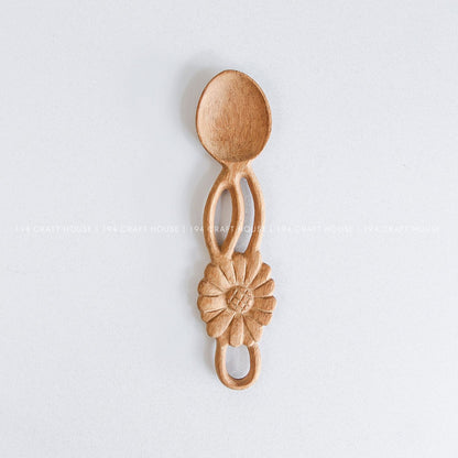 Handcarved wooden spoon with a decorative flower-shaped handle and natural wood grain