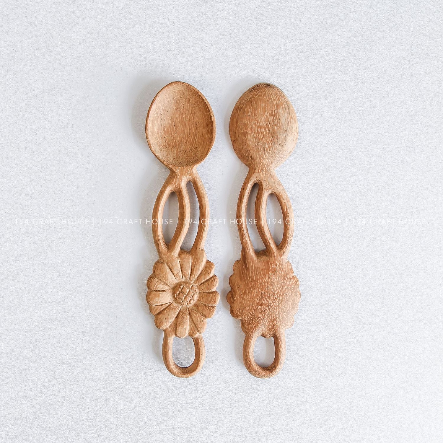 Three handcrafted wooden spoons with decorative flower-shaped handles and smooth natural wood finish