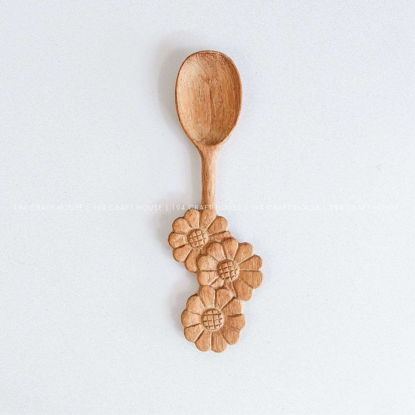 Handcrafted wooden spoon with a decorative three-flowers handle and natural wood grain