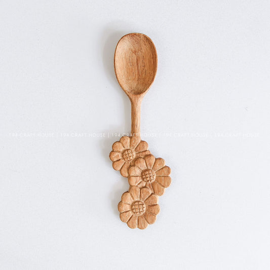 Handcrafted wooden spoon with a decorative three-flowers handle and natural wood grain
