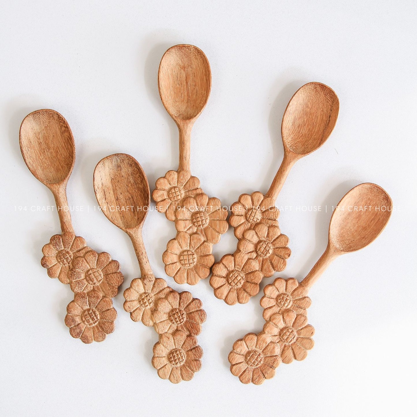 Assorted handcrafted wooden spoons with decorative three-flowers handles for cooking, serving, and kitchen decor