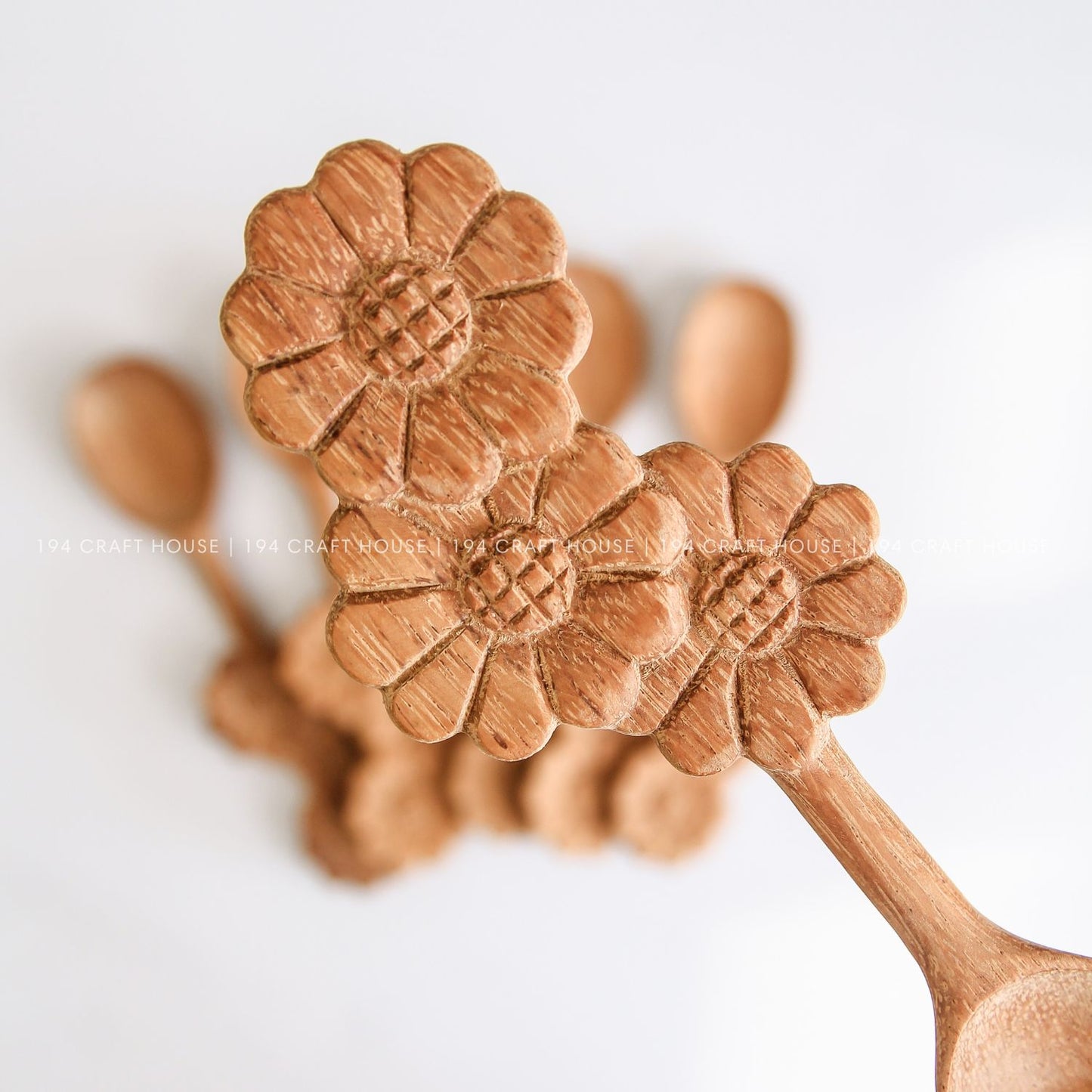 Collection of handcrafted wooden spoons with decorative three-flowers handles and natural wood grain