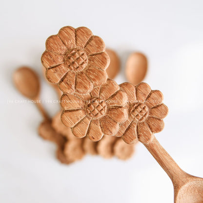 Collection of handcrafted wooden spoons with decorative three-flowers handles and natural wood grain