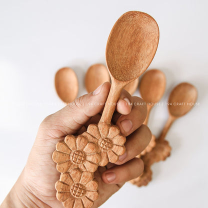 Handcrafted three-flowers handle wooden spoons held in hand to showcase their size and natural wood grain