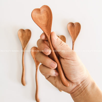 Hand holding a handcrafted wiggly heart-shaped wooden spoon