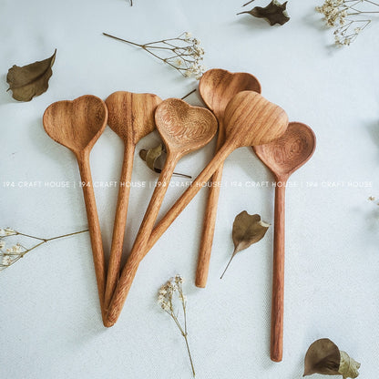 A set of heart-shaped wooden spoons arranged on a white surface with some decorative leaves around. The spoons are displayed against a neutral background with a watermark indicating the image was taken by '194 Craft House'.