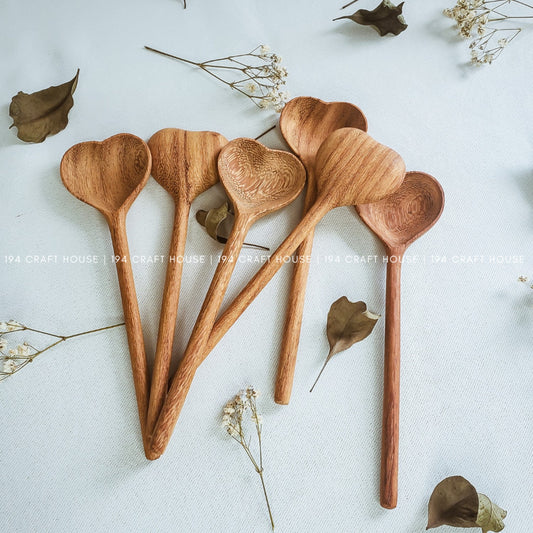 A set of heart-shaped wooden spoons arranged on a white surface with some decorative leaves around. The spoons are displayed against a neutral background with a watermark indicating the image was taken by '194 Craft House'.