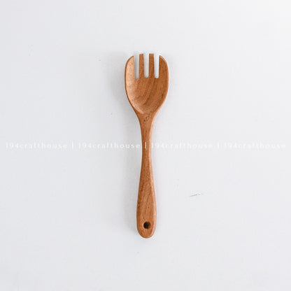 Single handcrafted wooden salad fork displayed vertically on a white background