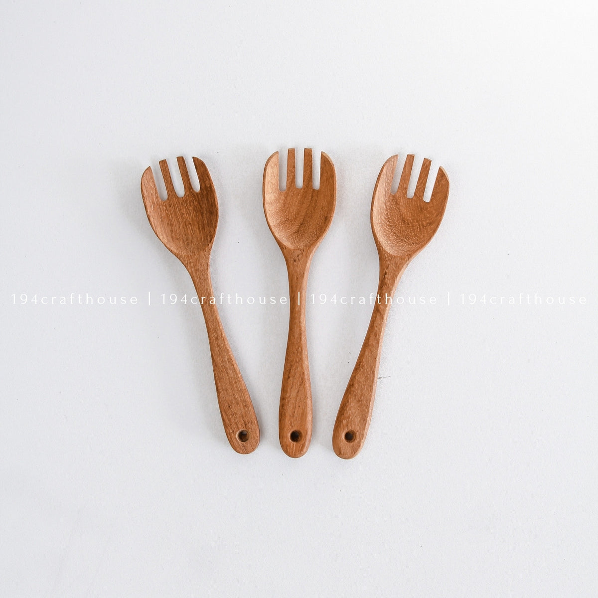 Three handcrafted wooden salad forks arranged upright on a white background