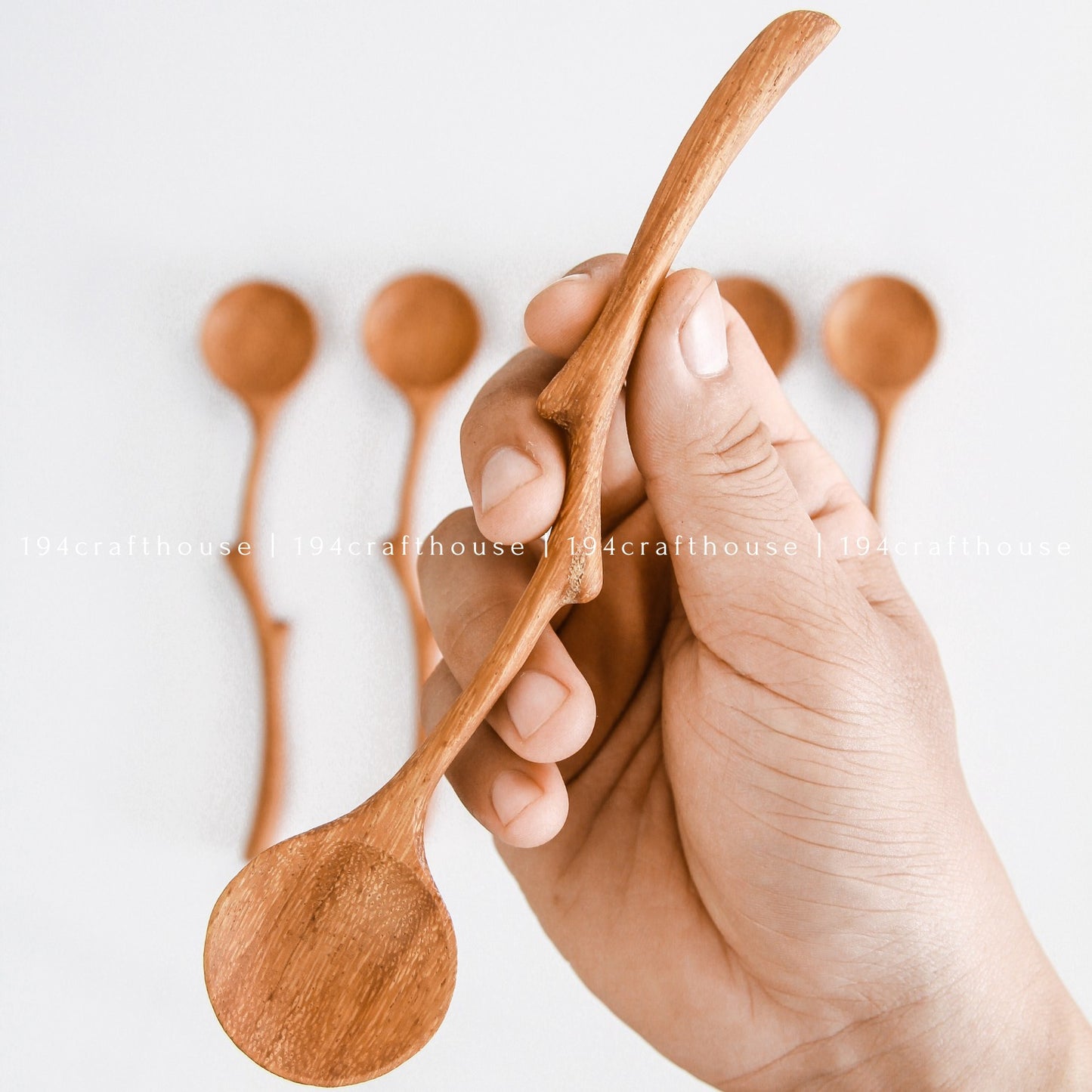 Branch handle wooden serving spoons held in hand showing different sizes and shapes