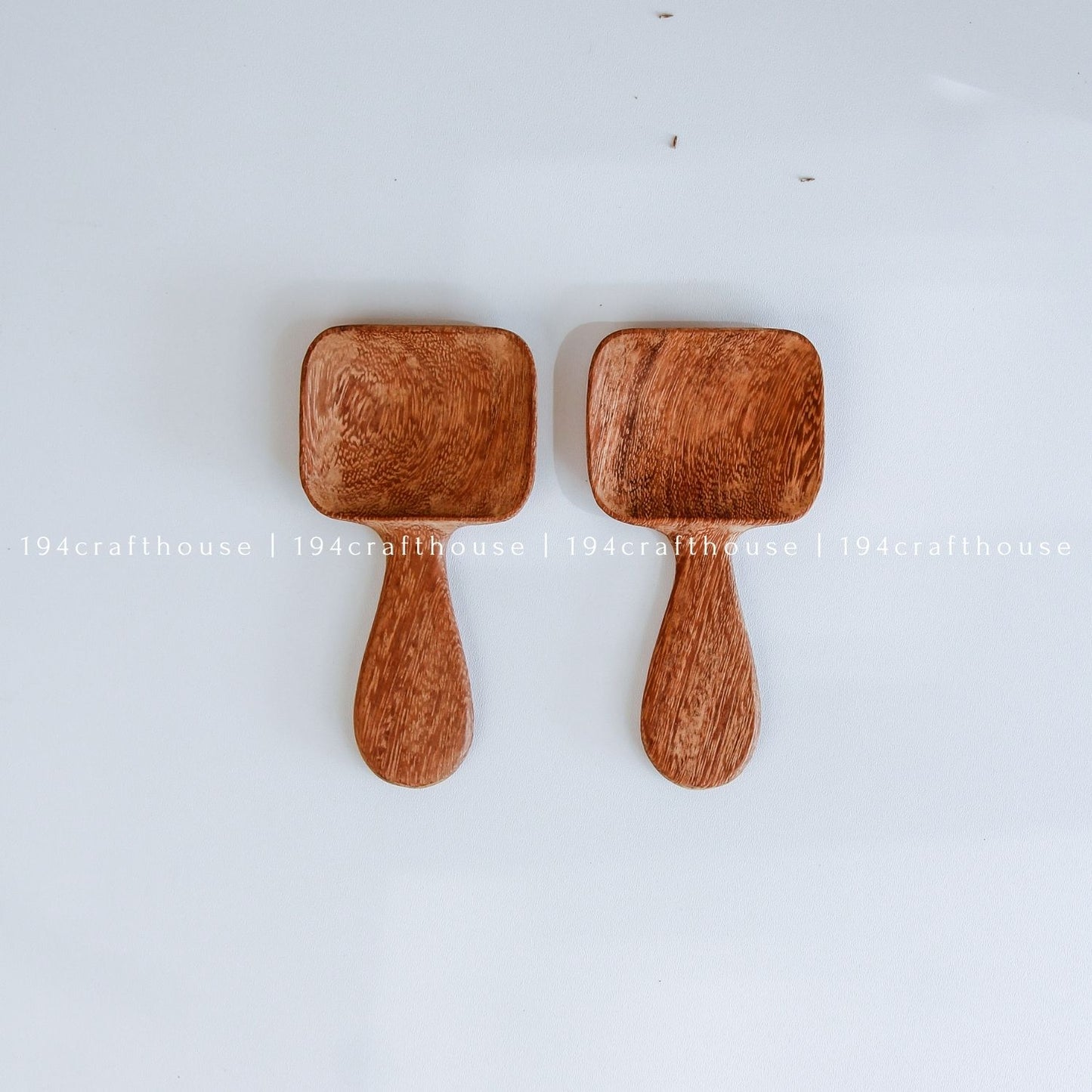 Handcarved Doussie wood measuring spoons with square scoops on a light gray background by 194 Craft House.
