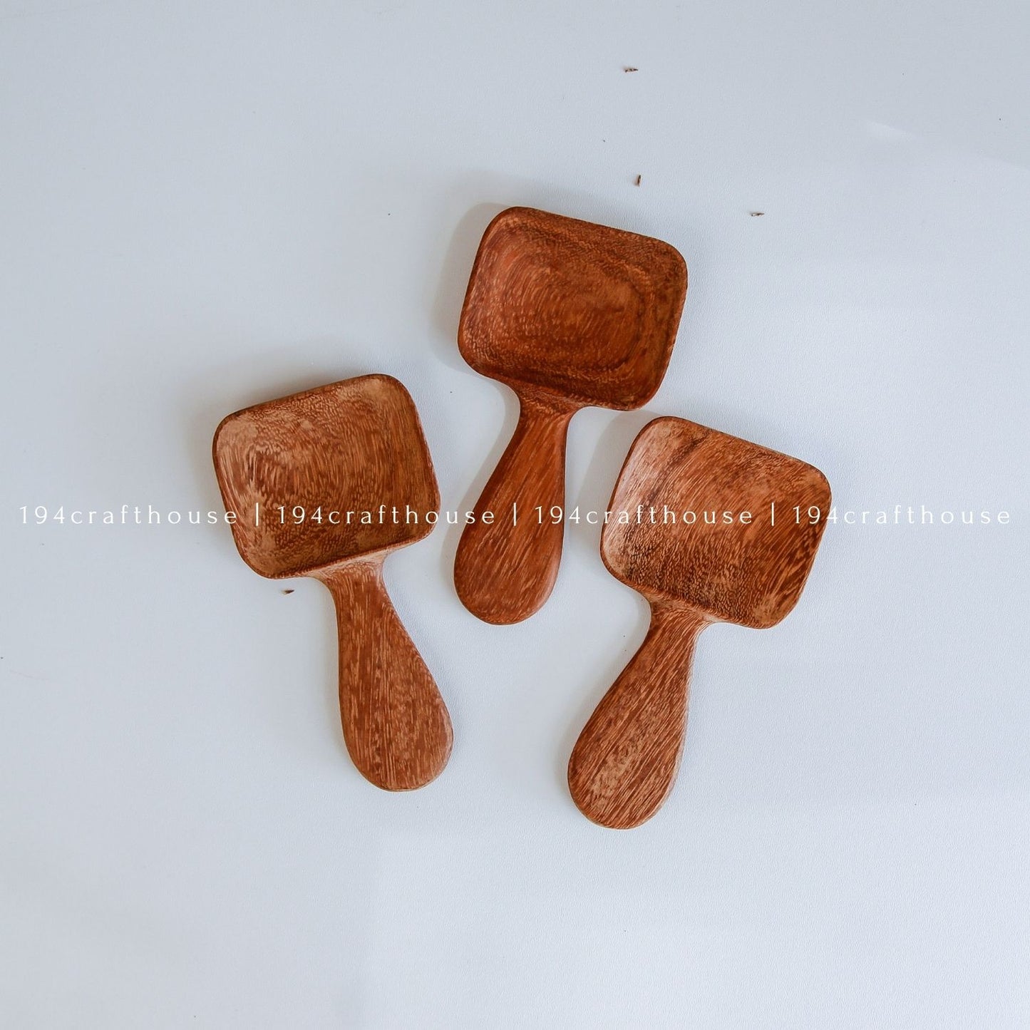 Handcarved Doussie wood measuring spoons with square scoops on a light gray background by 194 Craft House.