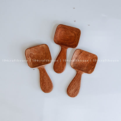 Handcarved Doussie wood measuring spoons with square scoops on a light gray background by 194 Craft House.