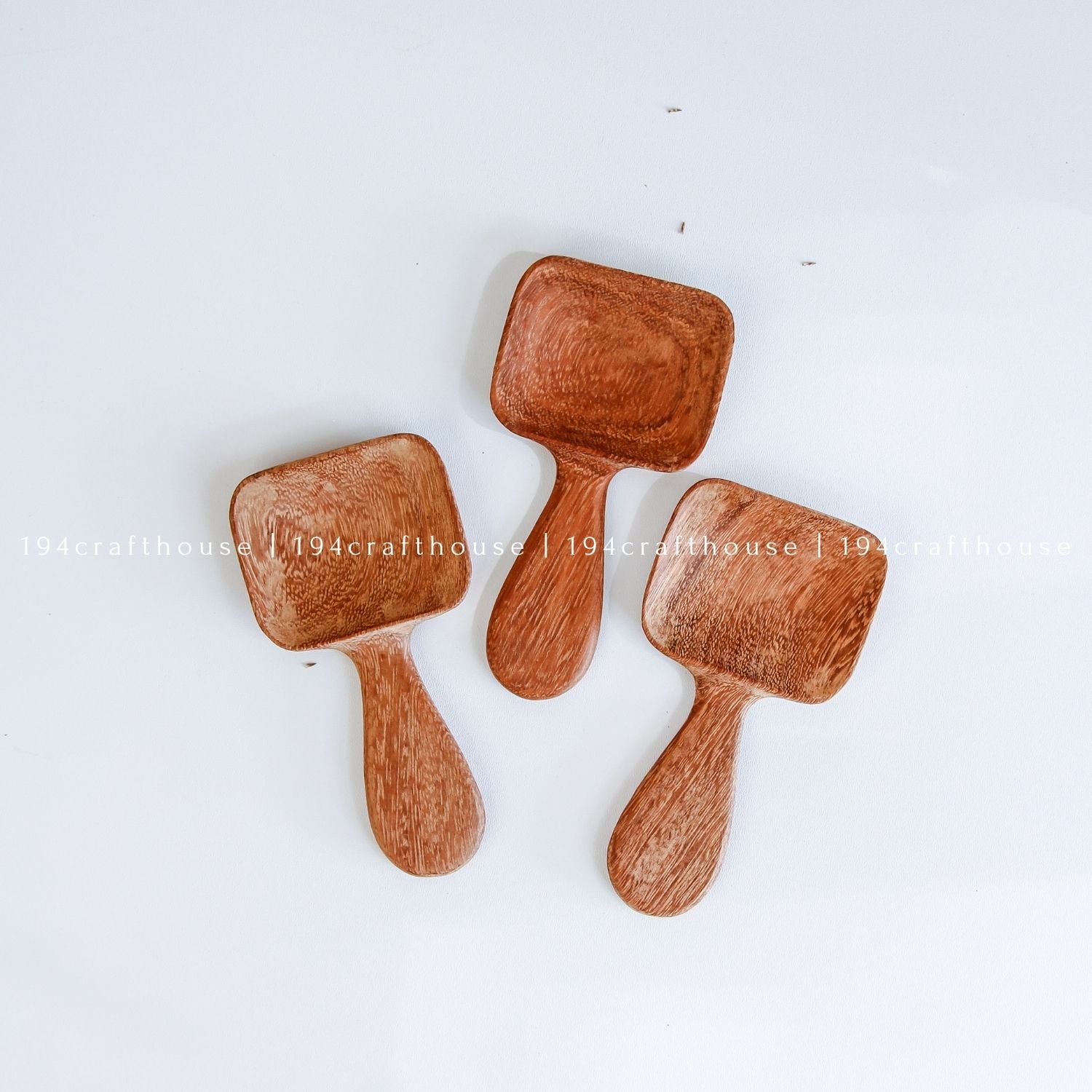 Handcarved Doussie wood measuring spoons with square scoops on a light gray background by 194 Craft House.