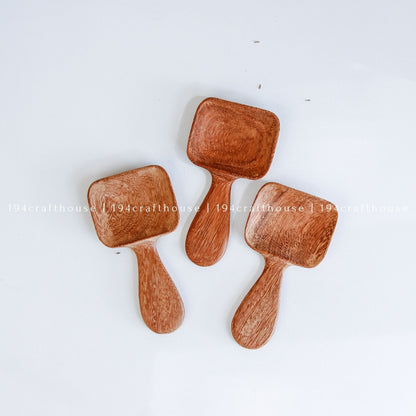 Handcarved Doussie wood measuring spoons with square scoops on a light gray background by 194 Craft House.