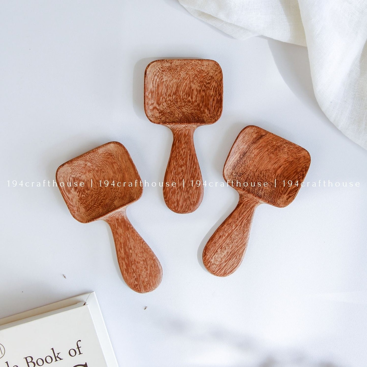 Handcarved Doussie wood measuring spoons with square scoops on a light gray background by 194 Craft House.