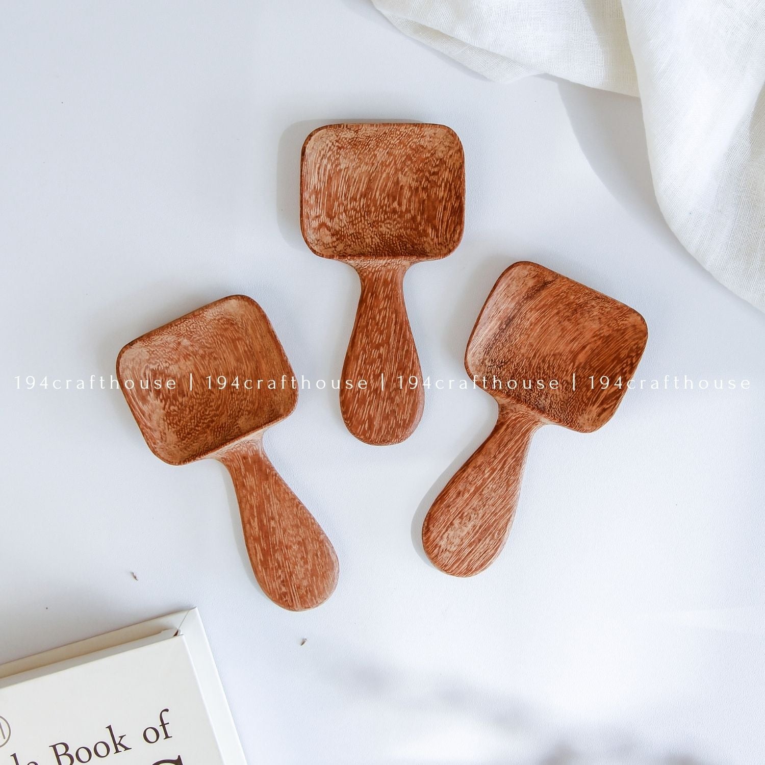 Handcarved Doussie wood measuring spoons with square scoops on a light gray background by 194 Craft House.