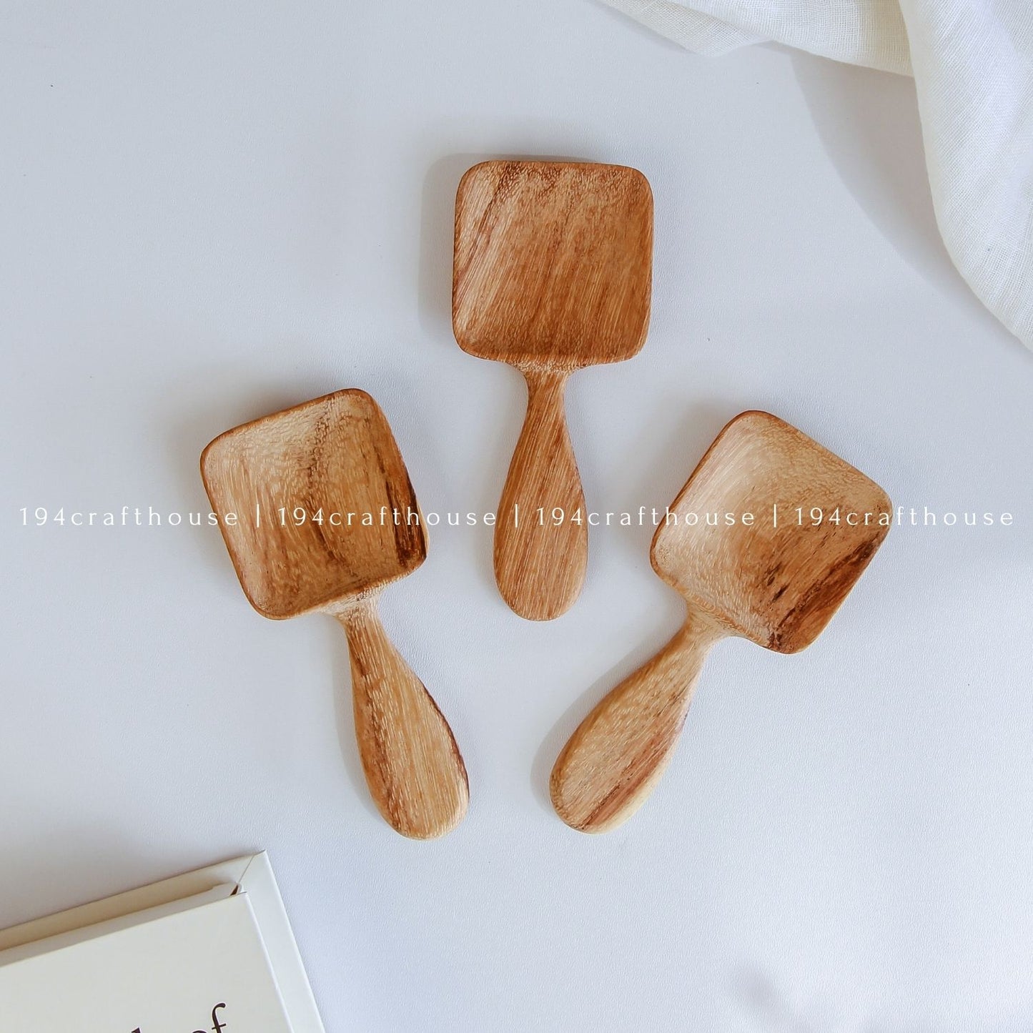 Handcarved Doussie wood measuring spoons with square scoops on a light gray background by 194 Craft House.