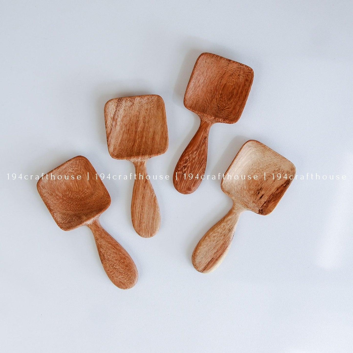 Handcarved Doussie wood measuring spoons with square scoops on a light gray background by 194 Craft House.