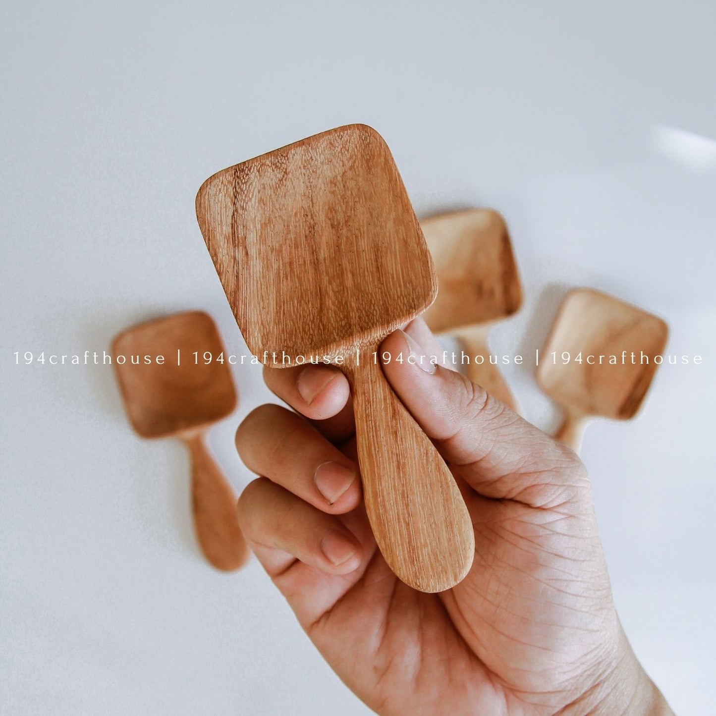 Handcarved Doussie wood measuring spoons with square scoops on a light gray background by 194 Craft House.
