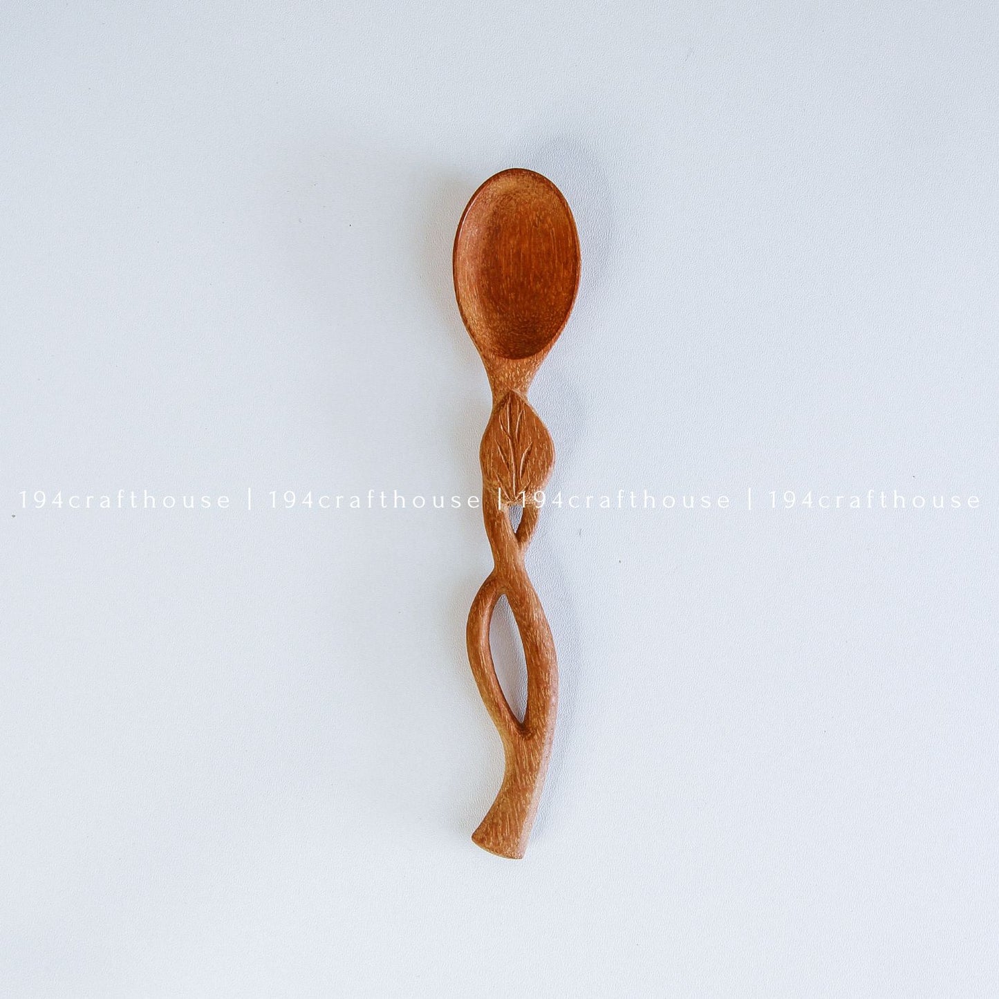 Hand-carved leaf handle wooden spoon with a small rounded bowl and botanical design