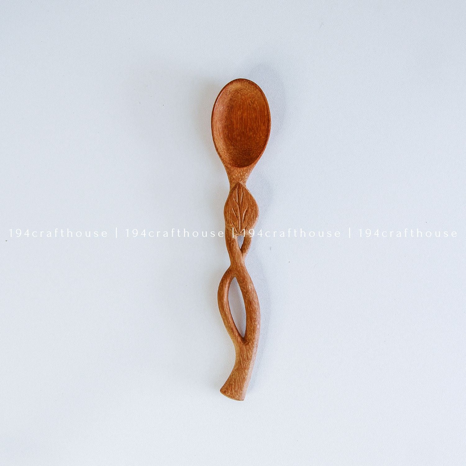 Hand-carved leaf handle wooden spoon with a small rounded bowl and botanical design