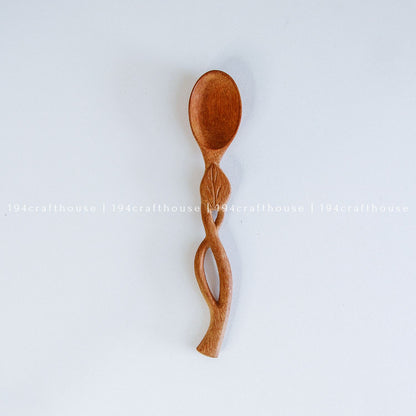 Hand-carved leaf handle wooden spoon with a small rounded bowl and botanical design