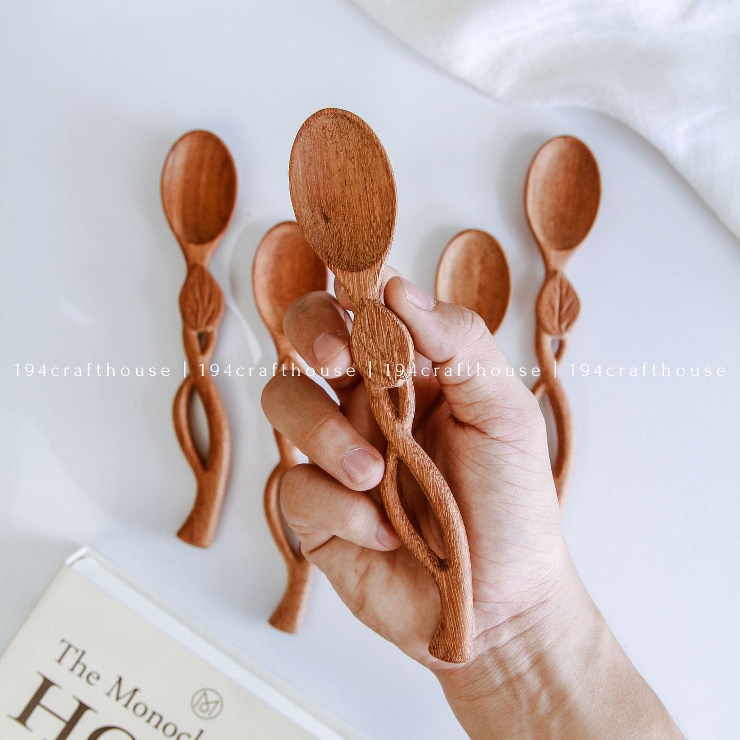 Hand holding handcrafted leaf handle wooden spoons with botanical carved details