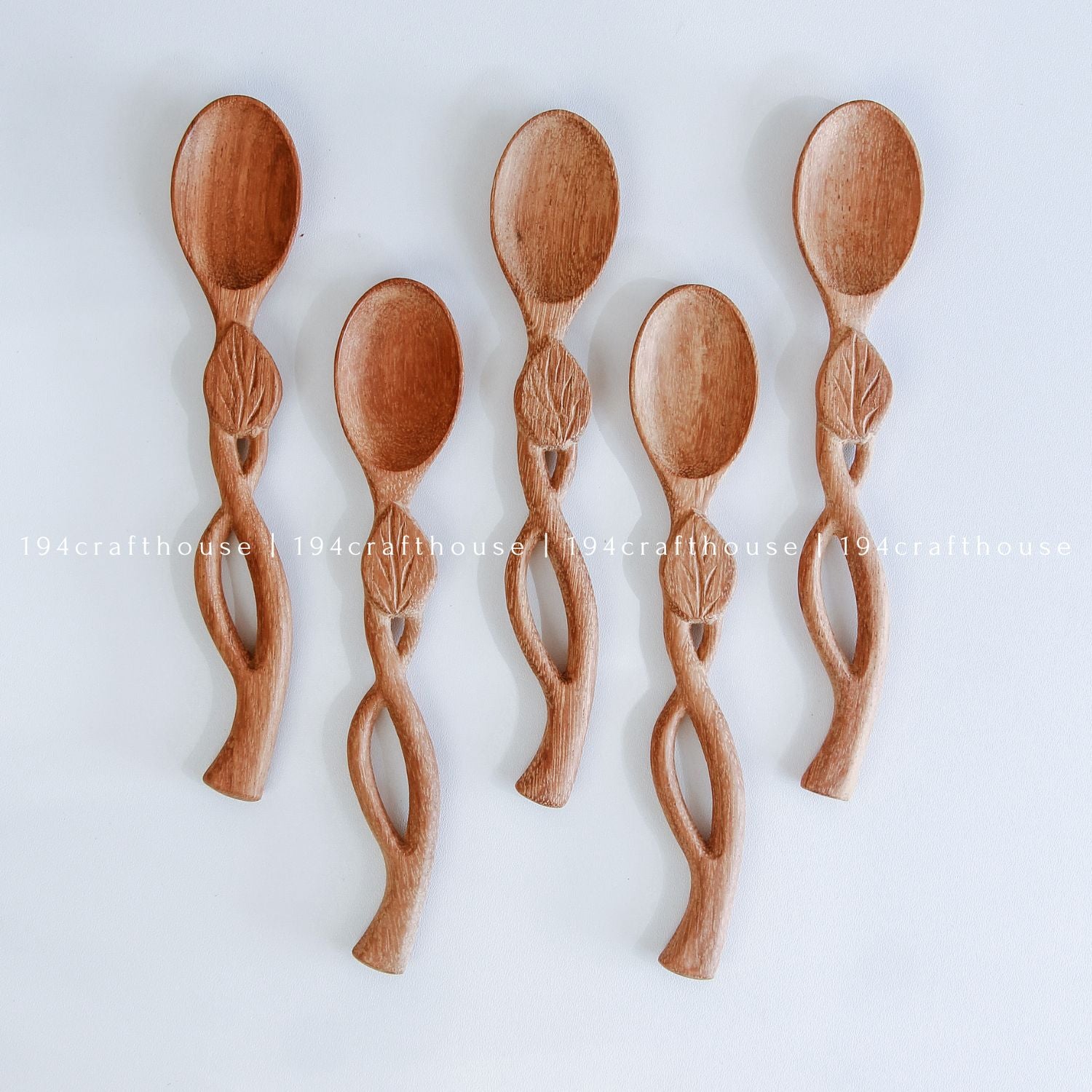 Handcarved Doussie wood measuring spoons with leaft handle on a light gray background by 194 Craft House.