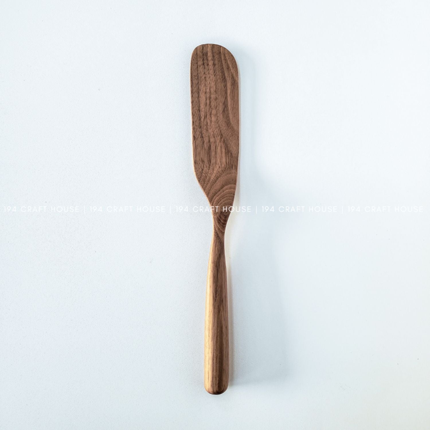 Front view of a walnut wooden spreader knife for butter and soft cheese